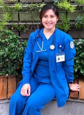 Young female student nurse in scrubs sitting in front of